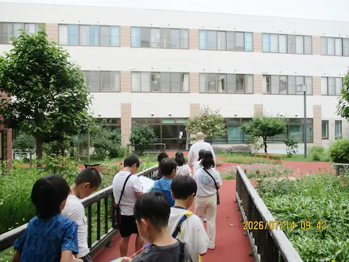 手稲山口小学校の児童のみなさんの施設見学。中庭の通路を歩いて見学する児童たち